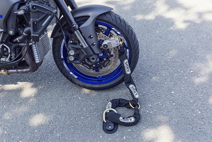 Motorcycle with security chain fitted to ground anchor