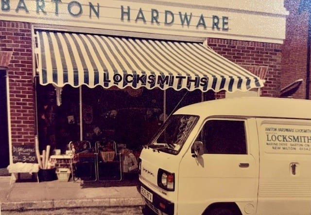 Shop front of Barton Hardware in Barton on Sea, with a branded locksmith van parked outside. The display windows are filled with hardware tools and security products — in Barton on Sea, where Paul Harper‑Smith's journey began.