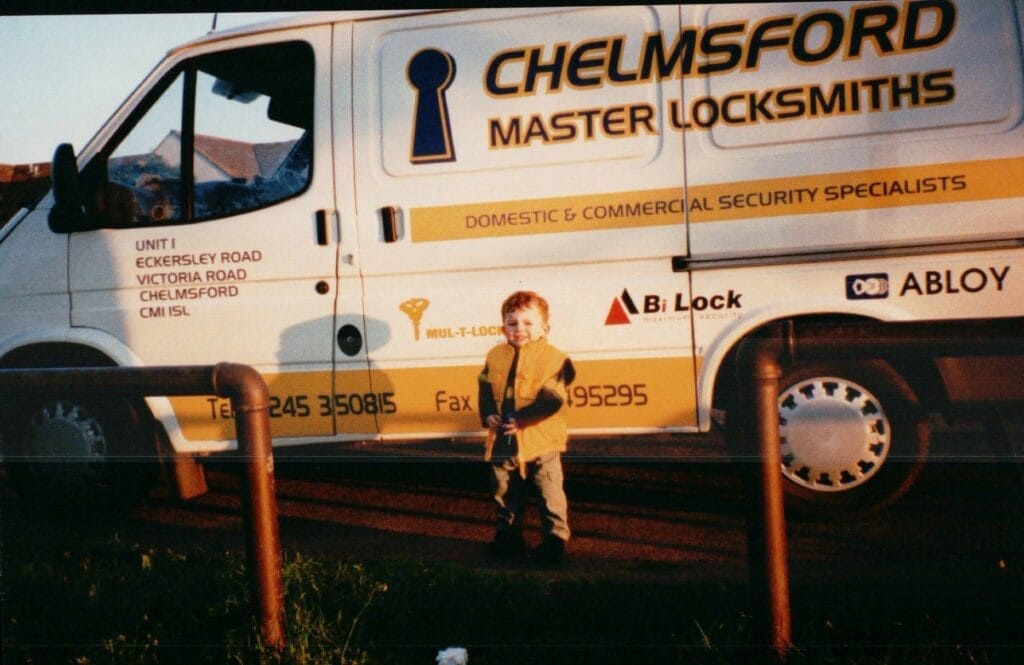 A young Alex Smith standing in front of the Chelmsford Master Locksmiths van